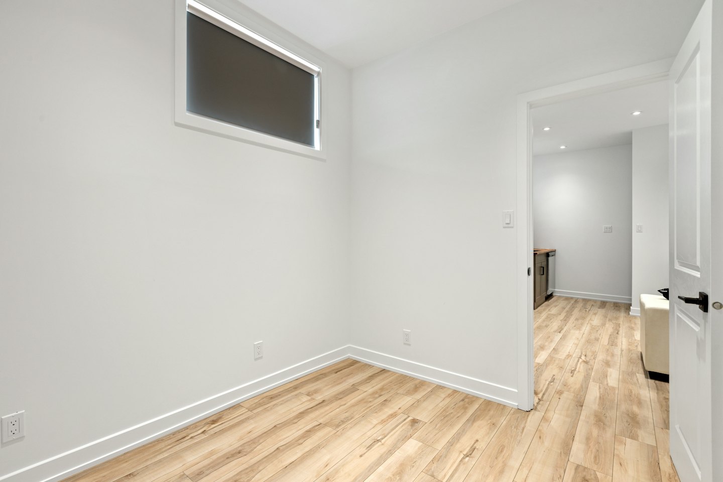 Neu renoviertes, leeres Zimmer mit hellem Holzboden und offener Tür.