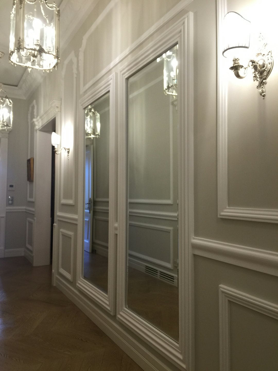 Eleganter Flur mit vertäfelten Wänden und verzierten Kronleuchtern.